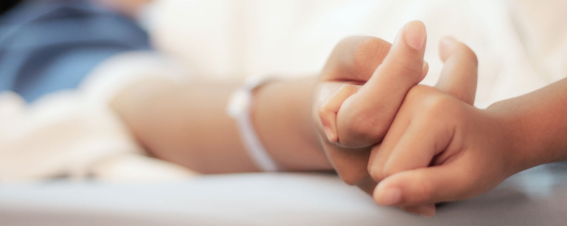 Die Hand einer Patientin des Klinikverbunds Allgäu wird von einer anderen Hand gehalten.