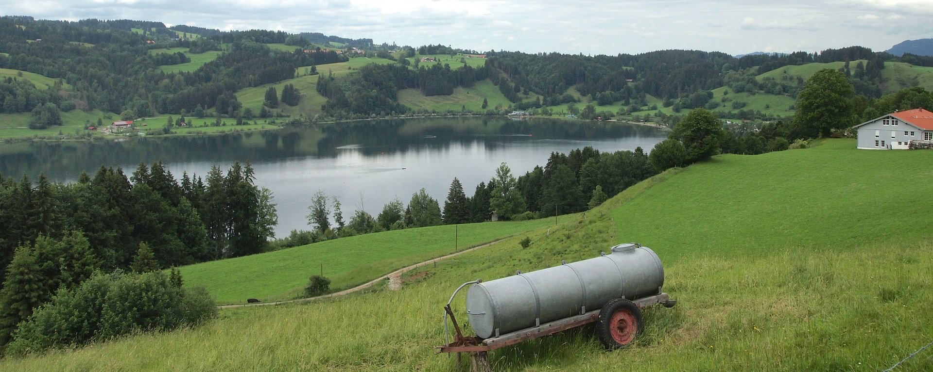 Blick auf einen See in Immenstadt. Im Vordergrund steht ein Wassertank.