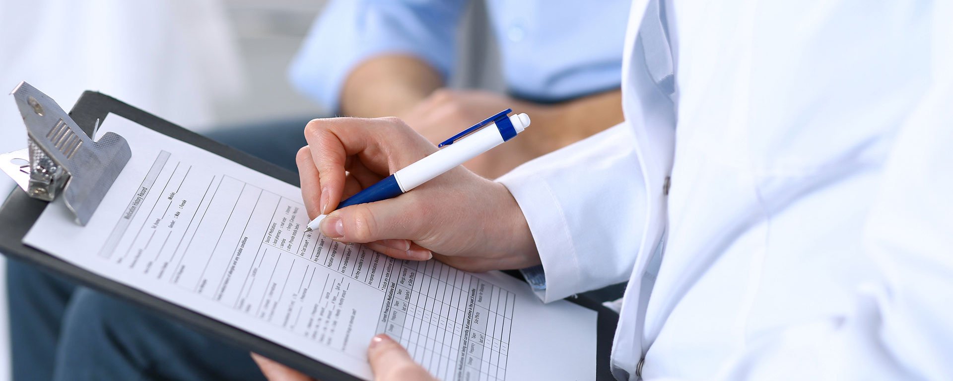 Ärztin des Klinikverbunds Allgäu hält ein Medizin- und Gesundheitskonzept in der Hand, während Sie es einem Patienten erklärt.