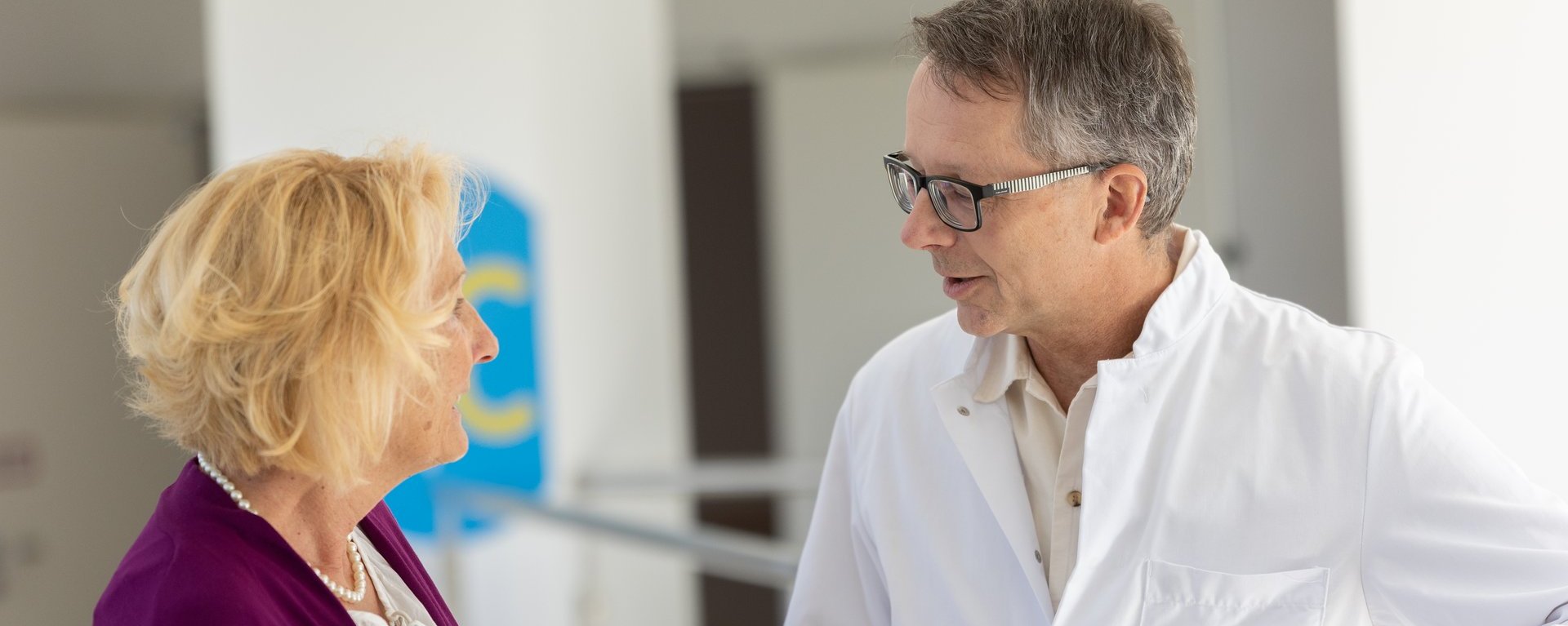 Ein Arzt im weißen Kittel führt ein Gespräch mit einer Patientin in einer Klinik.