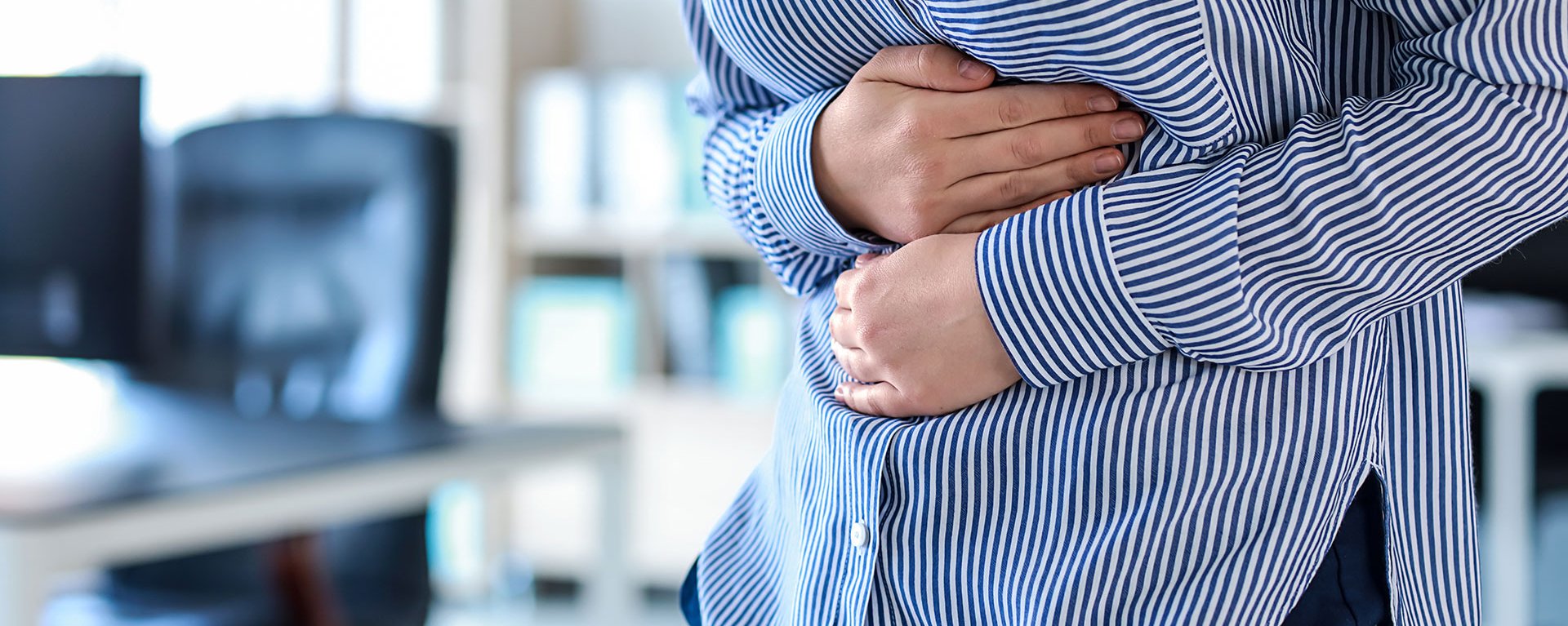 Junge Frau leidet unter Bauchschmerzen und hält sich den Bauch.