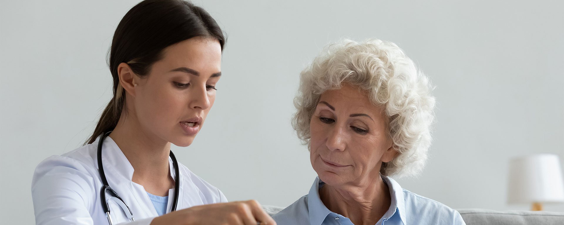 Eine junge Ärztin des Klinikverbunds Allgäu erklärt einer älteren Patientin einen Vertrag.
