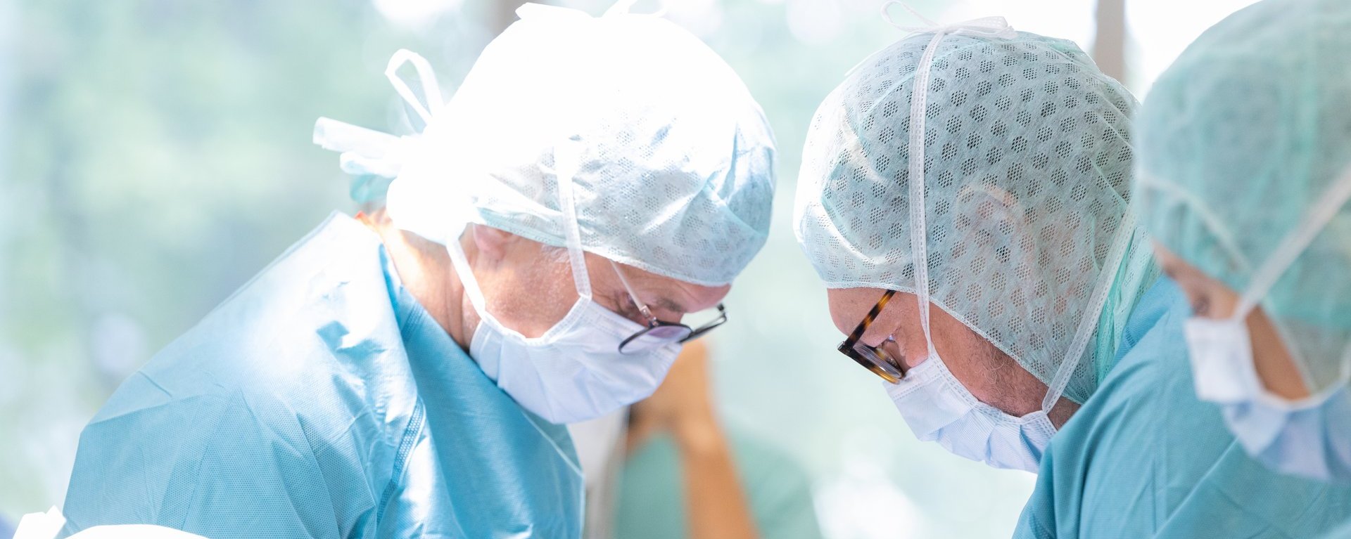 Zwei Ärzte aus dem Fachbereich Gefäßchirurgie am Klinikum Kempten beugen sich in voller Operationskleidung über einen Patienten Zwei Ärzte aus dem Fachbereich Gefäßchirurgie am Klinikum Kempten beugen sich in voller Operationskleidung über einen Patienten
