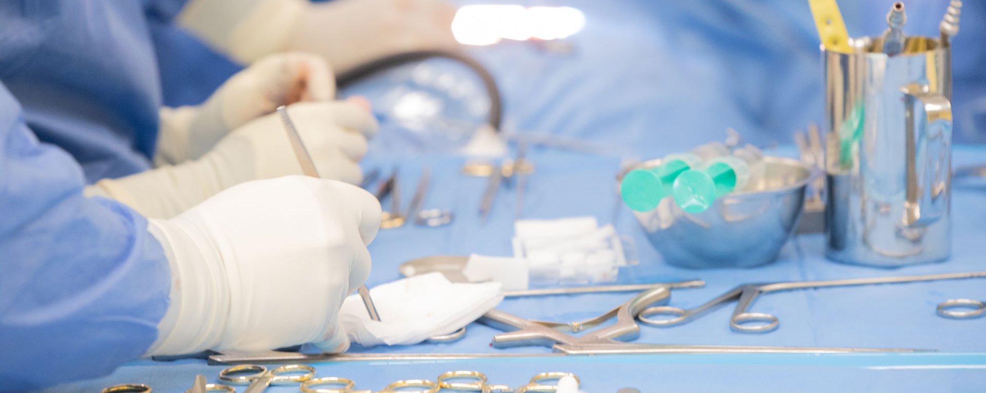Detailaufnahme von behandschuhten Händen und des OP-Tisches mit OP-Besteck während eines neurochirurgischen Eingriffs im Klinikverbund Allgäu