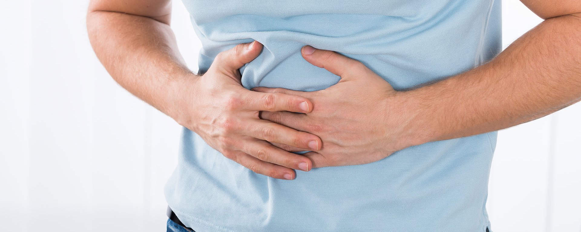 Ein Mann hält sich den Bauch, da er wahrscheinlich Magenschmerzen hat. Er wird im Klinikverbund Allgäu behandelt.