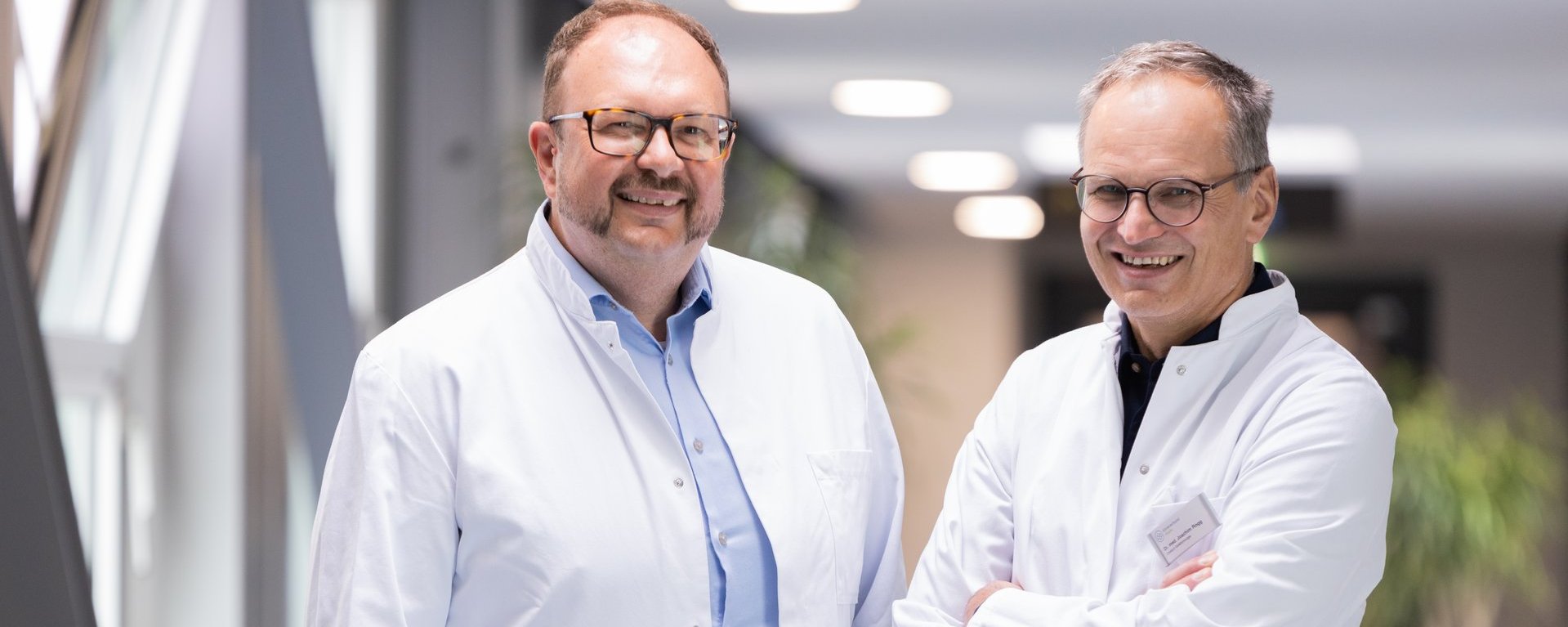 Dr. med. Roland Tines (links) und Dr. med. Joachim Rogg (rechts), Chefärzte des Fachbereichs Gefäßchirurgie am Klinikum Kempten auf einem Krankenhausflur Dr. med. Roland Tines (links) und Dr. med. Joachim Rogg (rechts), Chefärzte des Fachbereichs Gefäßchirurgie am Klinikum Kempten auf einem Krankenhausflur