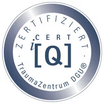 Rundes Zertifikatssiegel mit der Aufschrift ‚Zertifiziert – TraumaZentrum DGU – CERT iQ‘ in Blau und Silber.